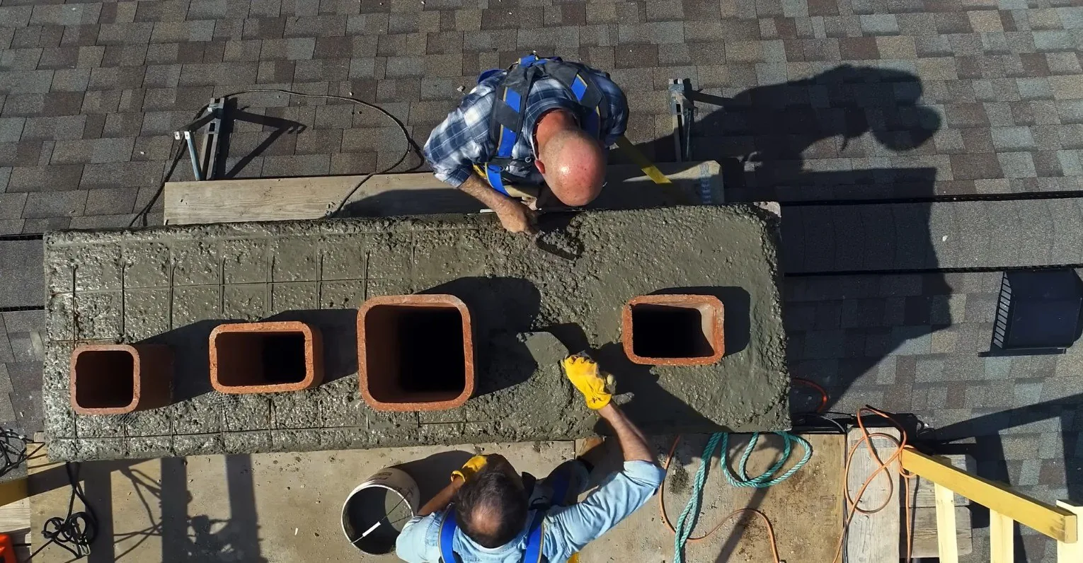 Two masons troweling a new chimney crown
